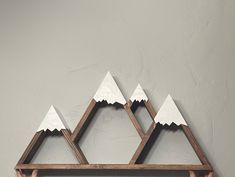 a wooden shelf with three white mountains on the top and one is hanging from it's side