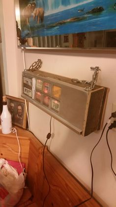 an old radio sitting on top of a wooden table next to a wall with pictures