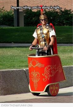 a man dressed as a roman gladiator riding on top of a red cart