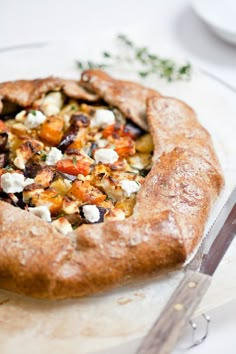 a pizza sitting on top of a white plate next to a knife and fork in front of it