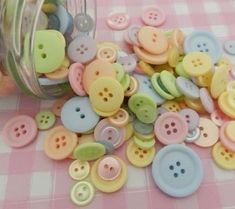 a jar full of buttons sitting on top of a pink and white checkered table cloth