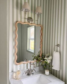 a bathroom sink sitting under a mirror next to a wall mounted faucet in front of a window