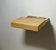 a wooden shelf with a pen holder attached to it's side against a wall