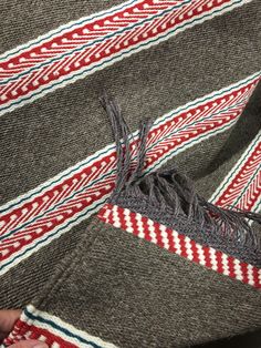 a close up of a person's hand holding a piece of fabric with red, white and blue stripes on it