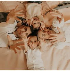 a group of people laying on top of a bed with their hands in the air