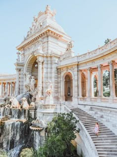 an ornate building with fountains and statues in front