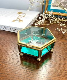 a glass box sitting on top of a wooden table next to a vase with flowers