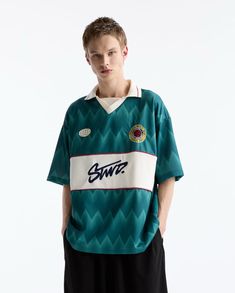 a young man standing in front of a white background wearing a green and white shirt