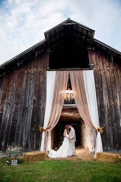 a bride and groom standing in front of a barn