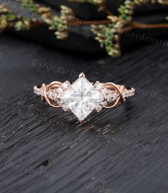 an engagement ring with a princess cut diamond in the center on top of a wooden table