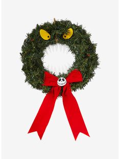 a christmas wreath with two eyes and a red bow hanging from it's side