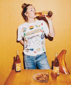 a woman drinking from a bottle while sitting at a table