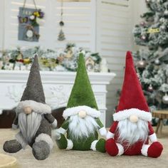 three gnomes sitting next to each other in front of a christmas tree