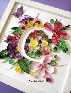 paper flowers and leaves are arranged in the shape of a letter g on a white frame