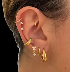 a woman wearing three different types of ear piercings