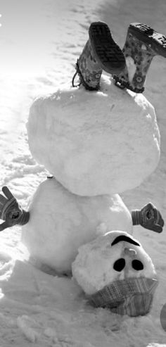 a snowman with skis on his head and feet sticking out of the snow