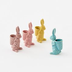 four small ceramic rabbits sitting next to each other in front of a white background,