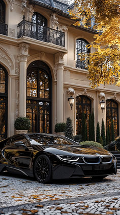 a black sports car parked in front of a large building with windows and balconies