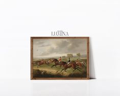 a painting hanging up on the wall next to a wooden frame with an image of horses racing