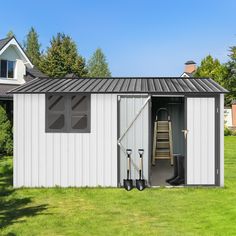 a white shed sitting in the middle of a lush green field