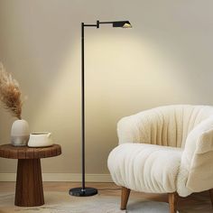 a white chair sitting next to a lamp on top of a wooden table in a living room