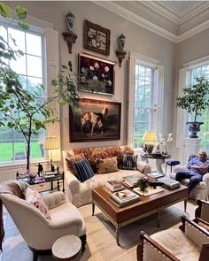 a living room filled with lots of furniture next to two large windows on the wall