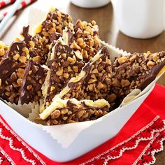 a bowl filled with chocolate and nuts on top of a red napkin next to a cup