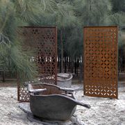 an old bathtub sitting in the middle of a park with trees around it and other metal structures