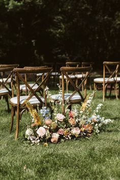 an outdoor ceremony setup with chairs and flowers on the grass, ready for guests to sit down