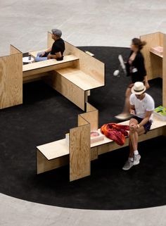 two people are sitting on benches in the middle of a circular area with black carpet