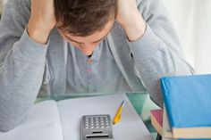 a man sitting at a desk with a calculator, notebook and pen in front of him