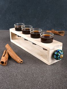 four shot glasses and cinnamon sticks on a wooden stand