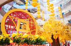 the interior of a shopping mall decorated with yellow flowers and lanterns hanging from the ceiling