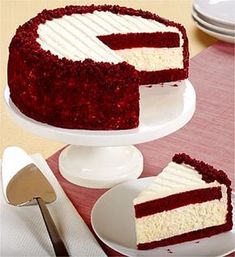 a red velvet cake with white frosting on a plate next to a knife and fork