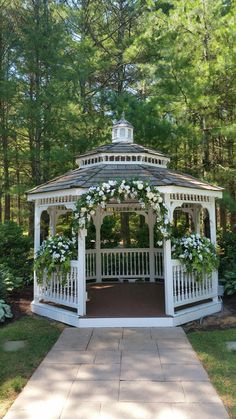 a gazebo with white flowers and greenery around it