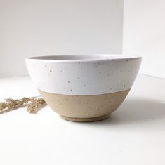 a white and brown bowl sitting on top of a table next to a bead