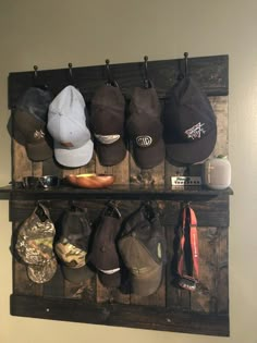 several hats are hanging on a wooden rack with hooks and other items in it, including baseball caps