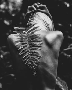 the back of a woman's head with a fern leaf on her shoulder, in black and white