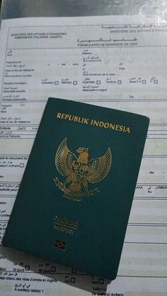 a green passport sitting on top of a document