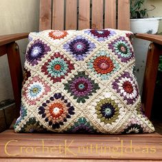 a crocheted pillow sitting on top of a wooden bench