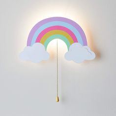 a rainbow shaped light hanging from the side of a white wall next to a cloud