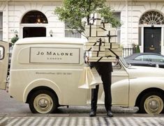 a man standing in front of a white van with luggage on it's back