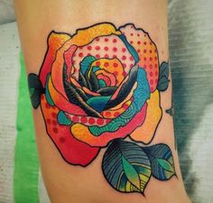 a colorful rose tattoo on the right side of the leg, with dots and leaves around it