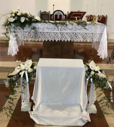 the altar is decorated with white flowers and greenery