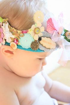 a close up of a baby wearing a headband with flowers and buttons on it