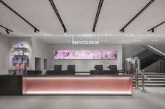 the front desk of a service desk is lit up with pink lights and black chairs