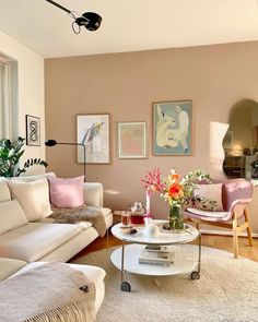 a living room filled with white furniture and lots of pink flowers on top of a table