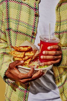 a man holding a plate of food and a drink in his hands with both hands