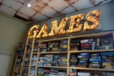 there is a sign that says games on the wall in front of shelves full of video games