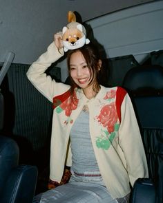 a woman sitting in the back seat of a car with a stuffed animal on her head